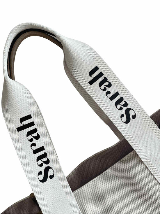 Canvas ribbon handles on the personalised tote bag which has the customers name imprinted all the way up the handles