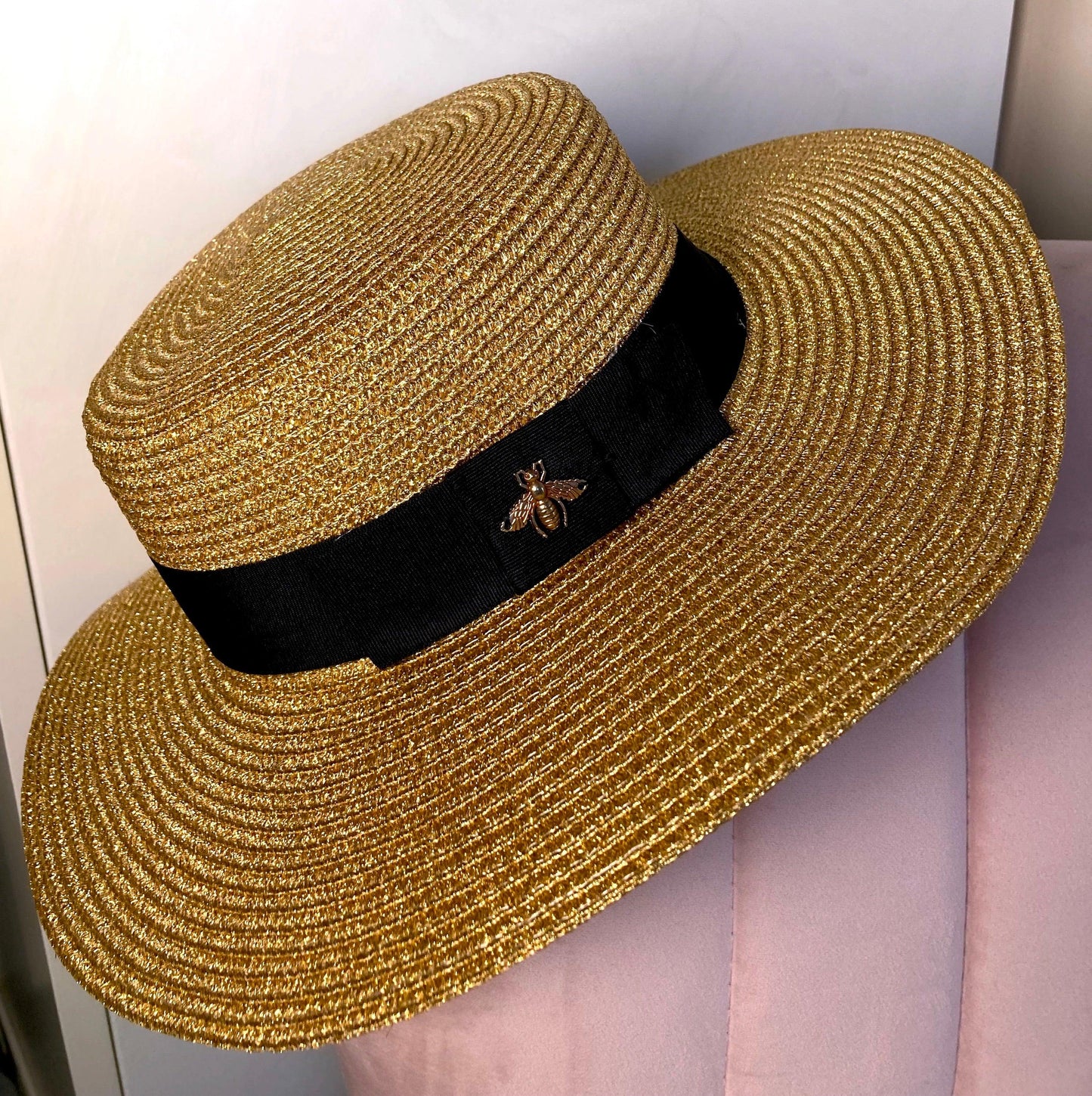 Straw Summer Hat with a gold Bee perched on furniture